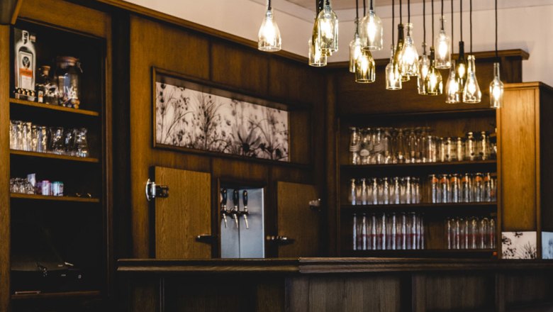 &Uacute;tuln&yacute; bar s dreven&yacute;m interi&eacute;rom a z&aacute;vesn&yacute;mi lampami na fľa&scaron;e.