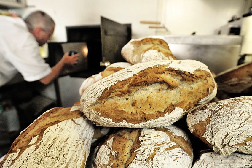 Čerstvo upečený chlieb pred pekárom, ktorý obsluhuje pec.