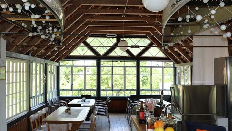 Pohľad do interiéru svetlej miestnosti s drevenou strechou a veľkými oknami.