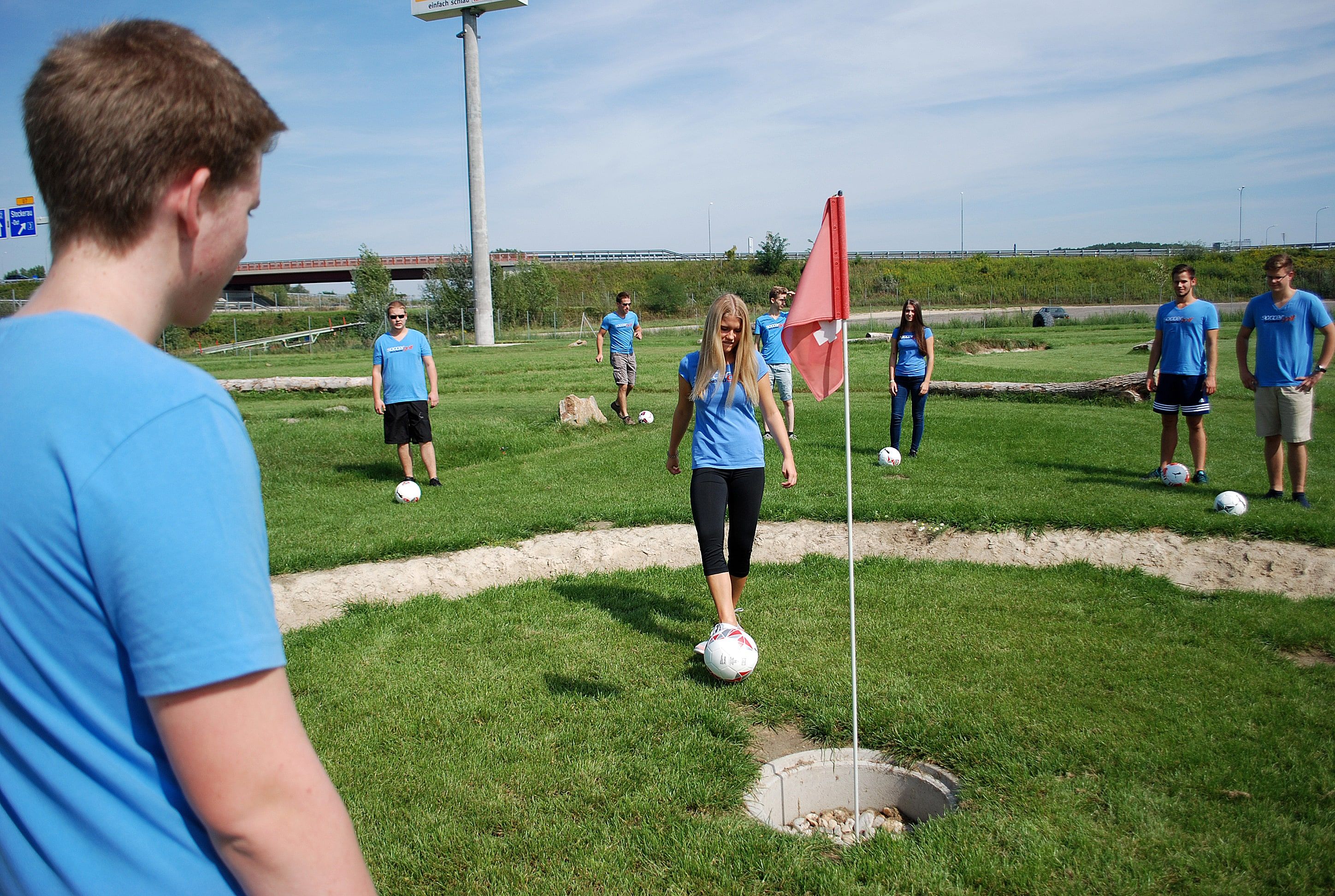 Skupina mladých ľudí hrajúcich Soccergolf.
