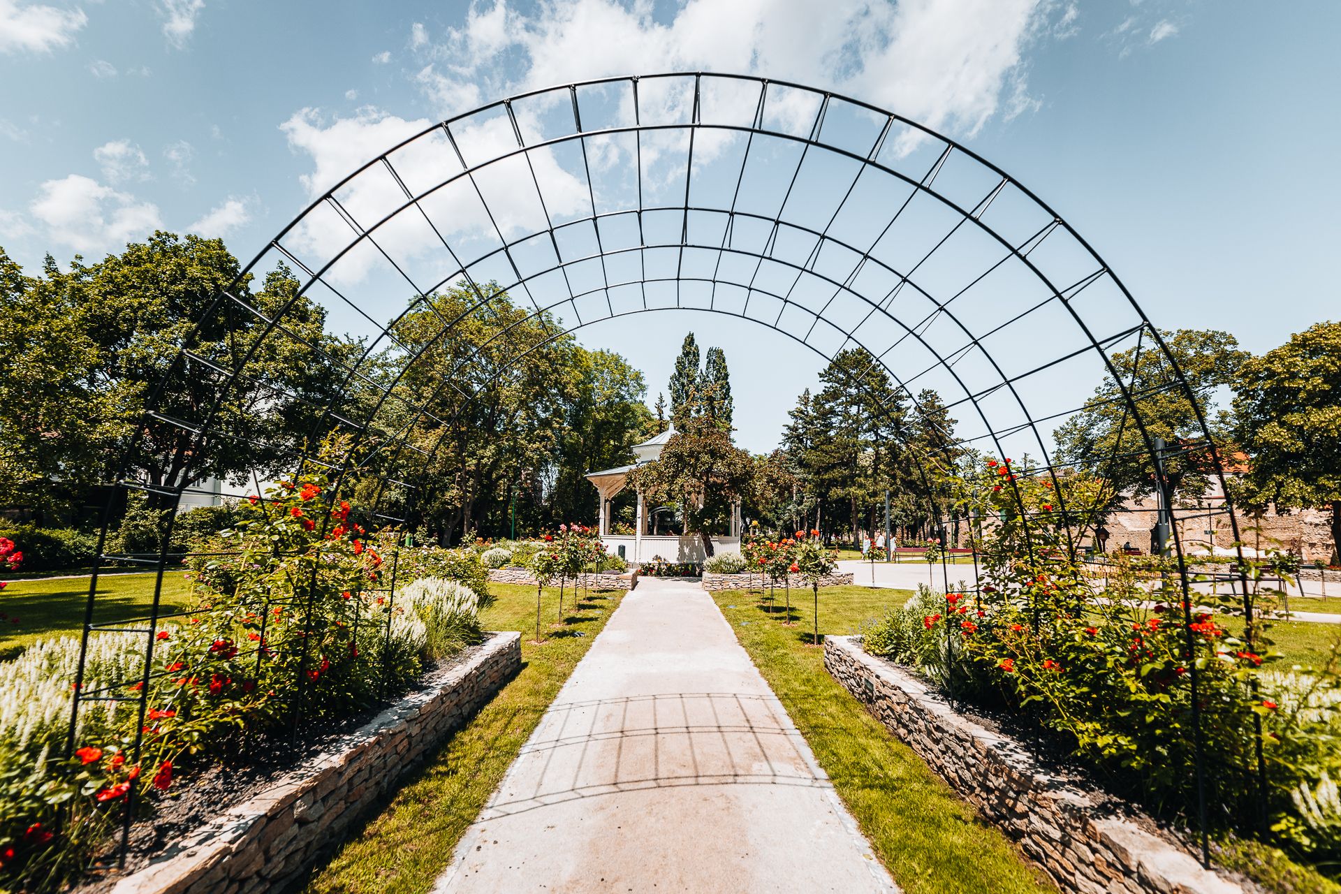 Zelený mestský park s romantickým pavilónom, ružovou záhradou a mriežkovým oblúkom