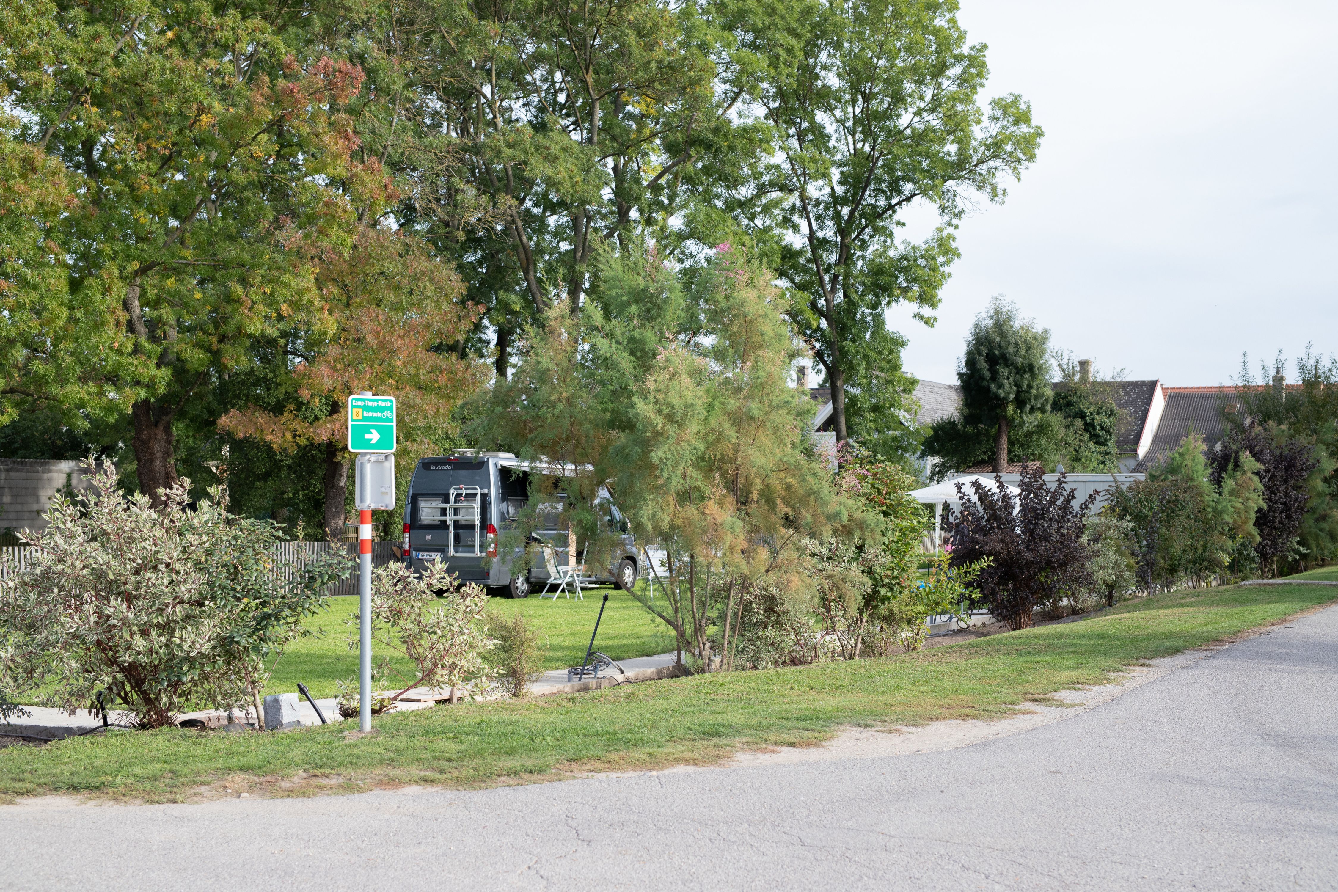 Kemp s karavanom a stromami v pozadí.