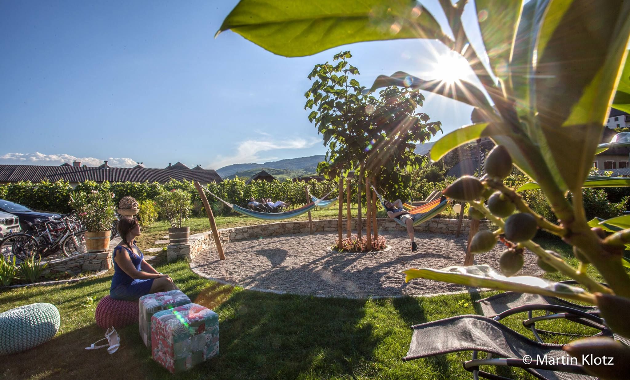 Stredomorská záhrada s hojdacími sieťami a relaxujúcimi ľuďmi.