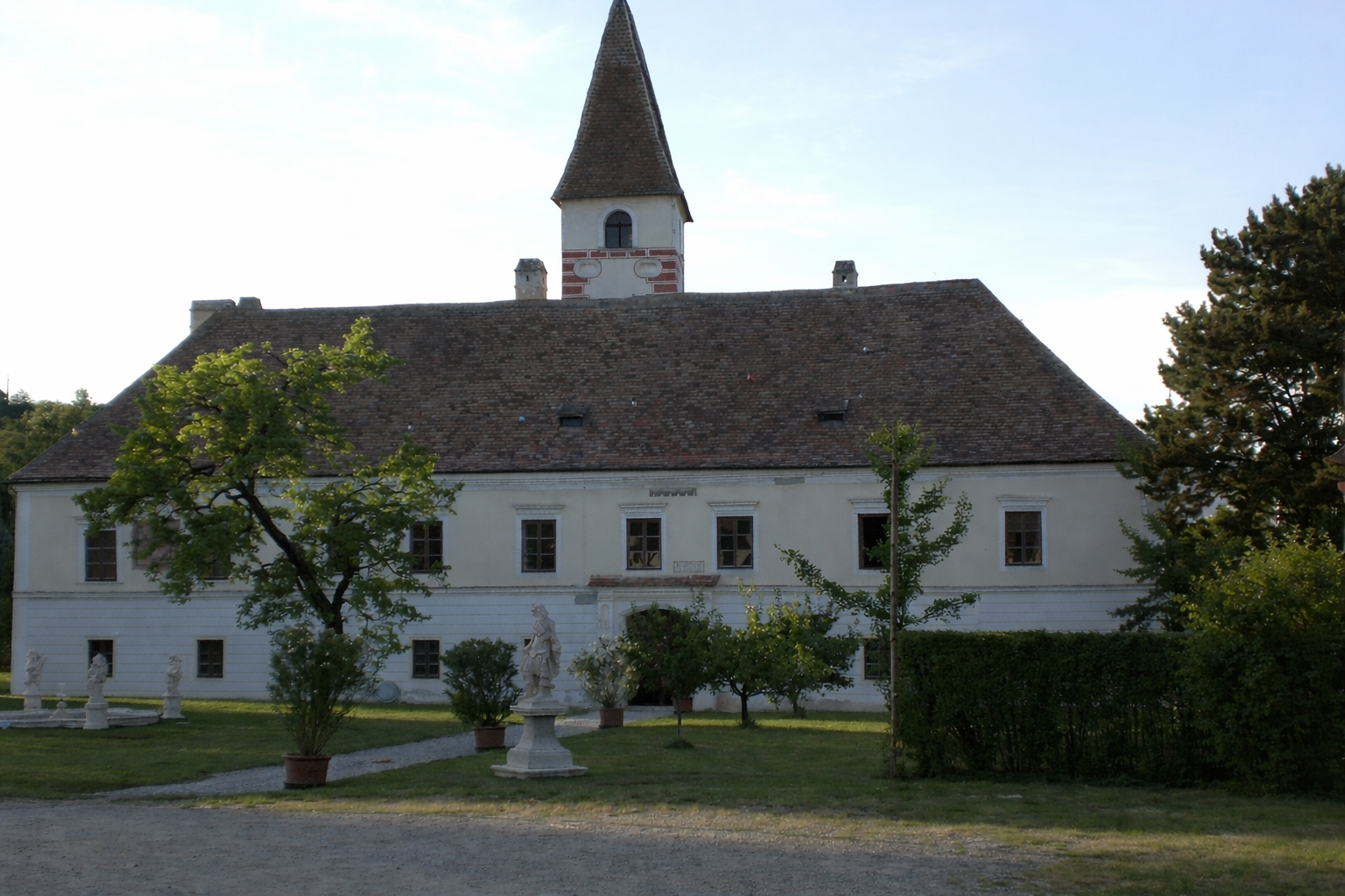 Hrad Limberg so záhradou a sochami v popredí.
