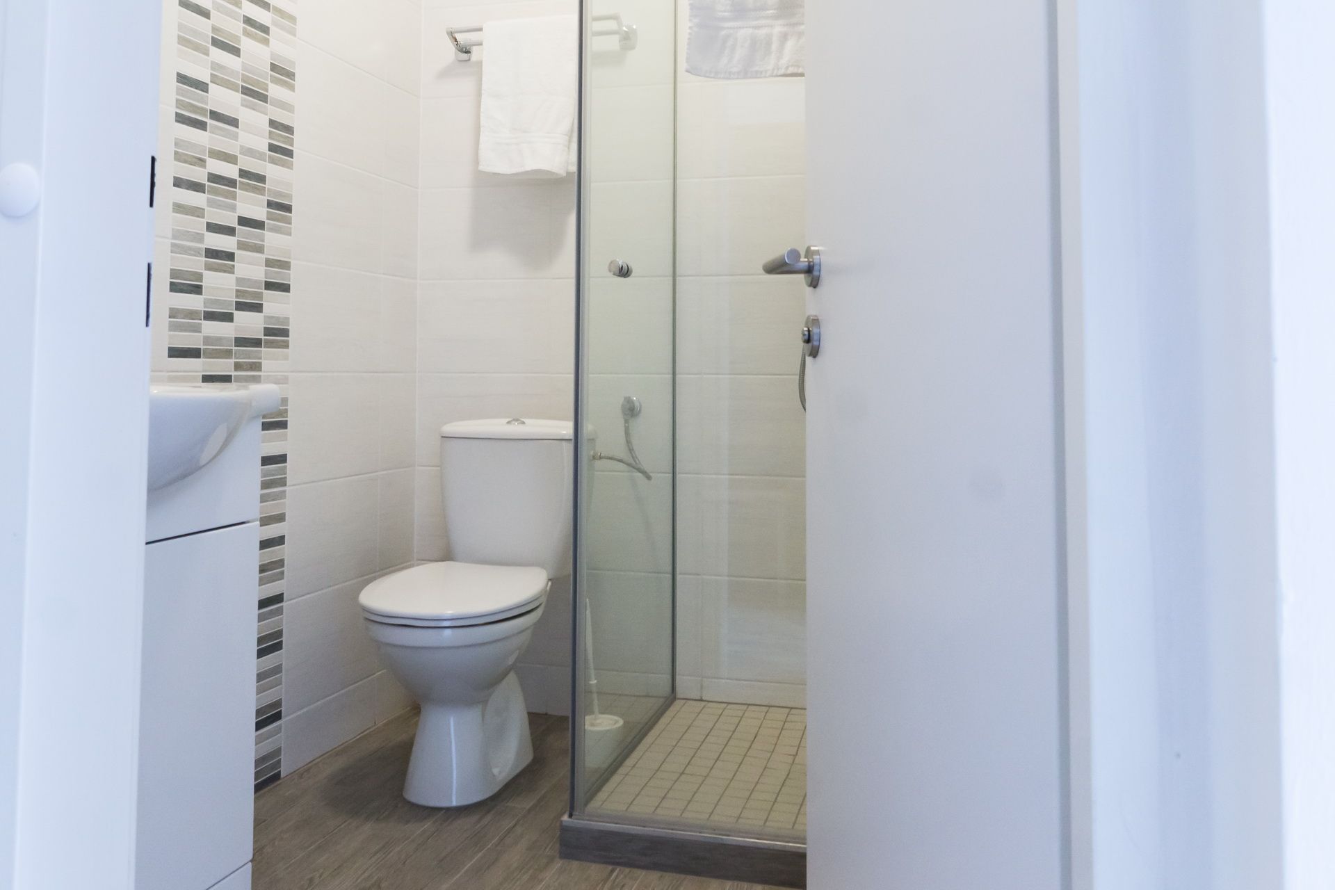 Moderná kúpeľňa s WC, sprchovacím kútom a uterákom.