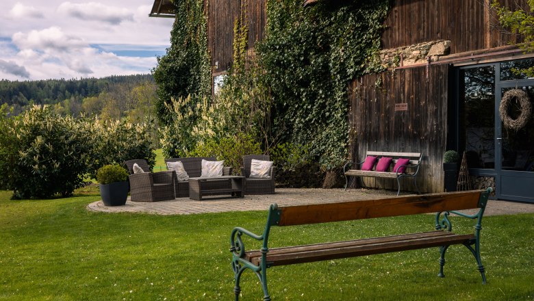 Z&aacute;hrada s poseden&iacute;m pred drevenou budovou porastenou brečtanom.