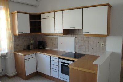 Malá kuchyňa s bielymi skrinkami, sporákom a kávovarom.
