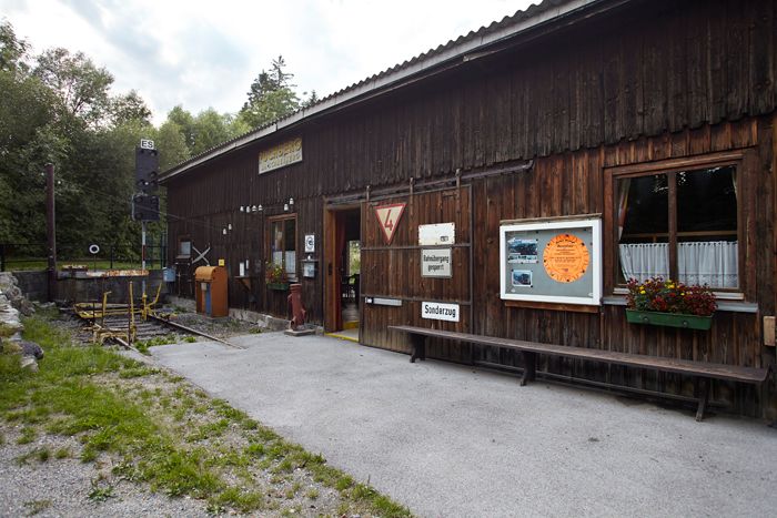 Drevená budova s nápismi a kvetmi, súčasť výstavy.