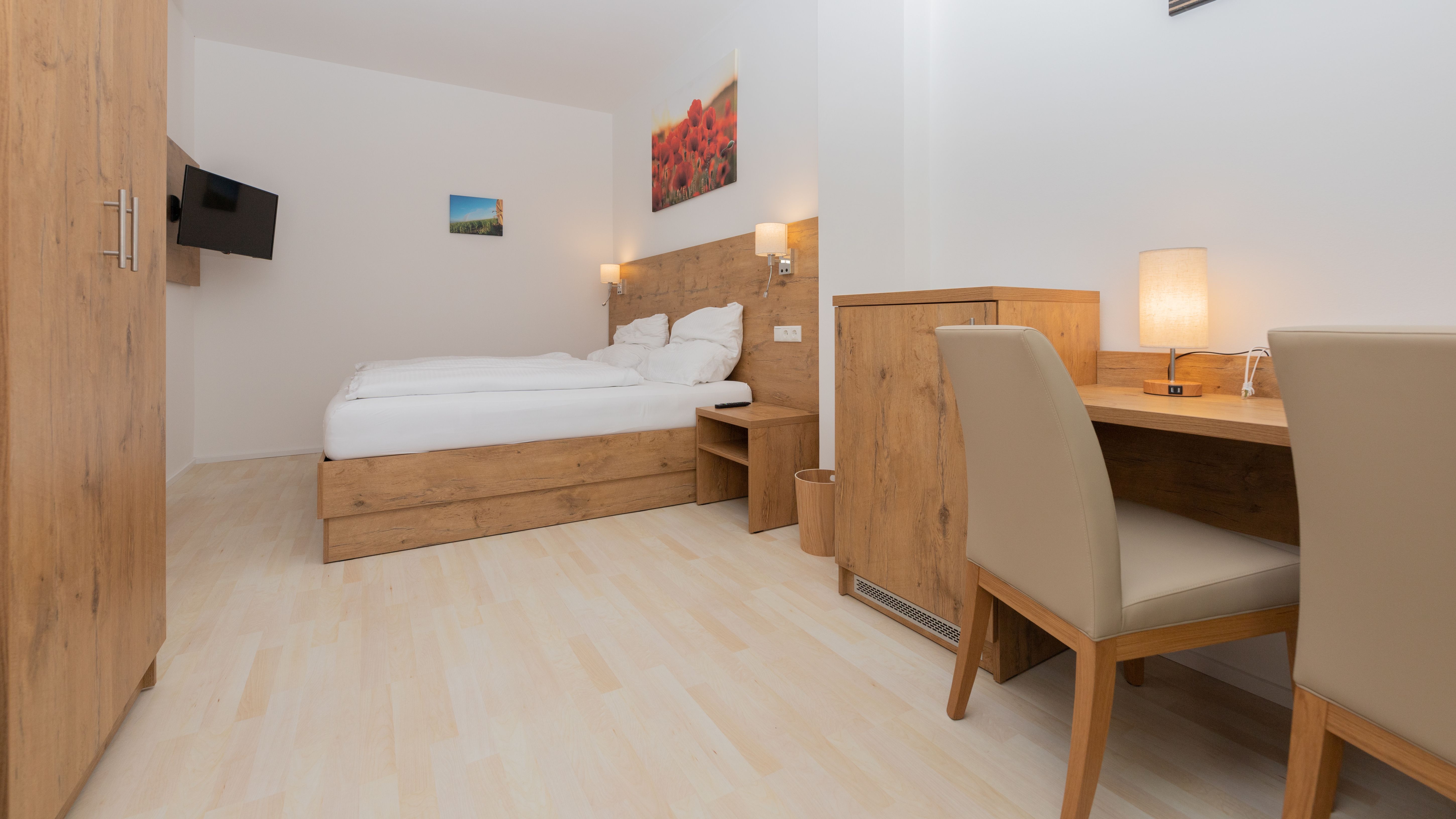 Moderná spálňa s dreveným nábytkom, manželskou posteľou, písacím stolom a TV s plochou obrazovkou.