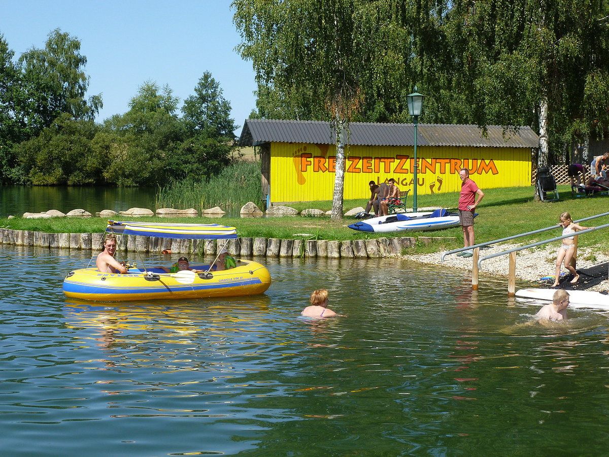 Ľudia sa pri jazere Bergwerksee Langau venujú voľnočasovým aktivitám.