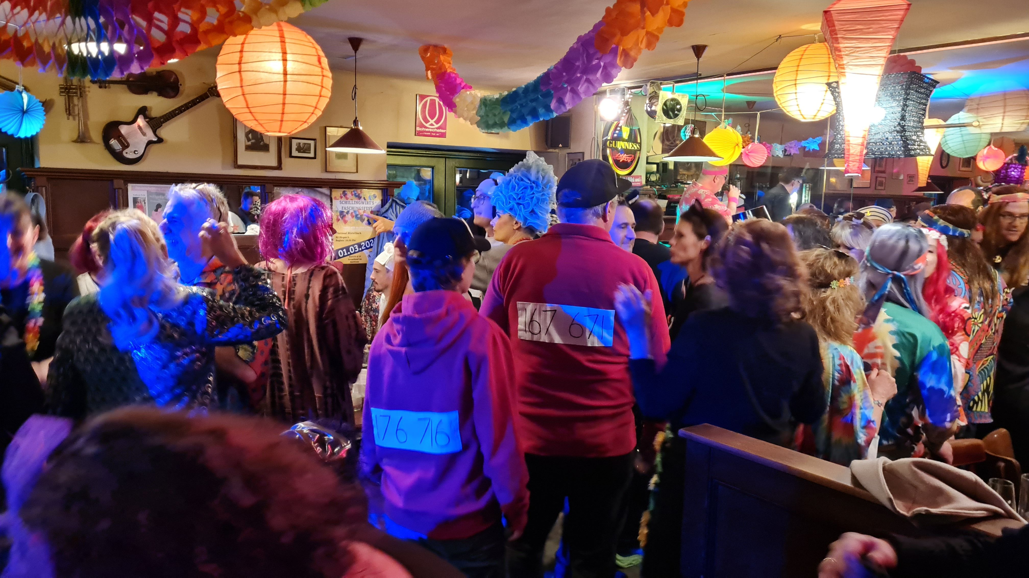 Ľudia v pestrých kostýmoch oslavujú karneval vo vyzdobenej miestnosti.
