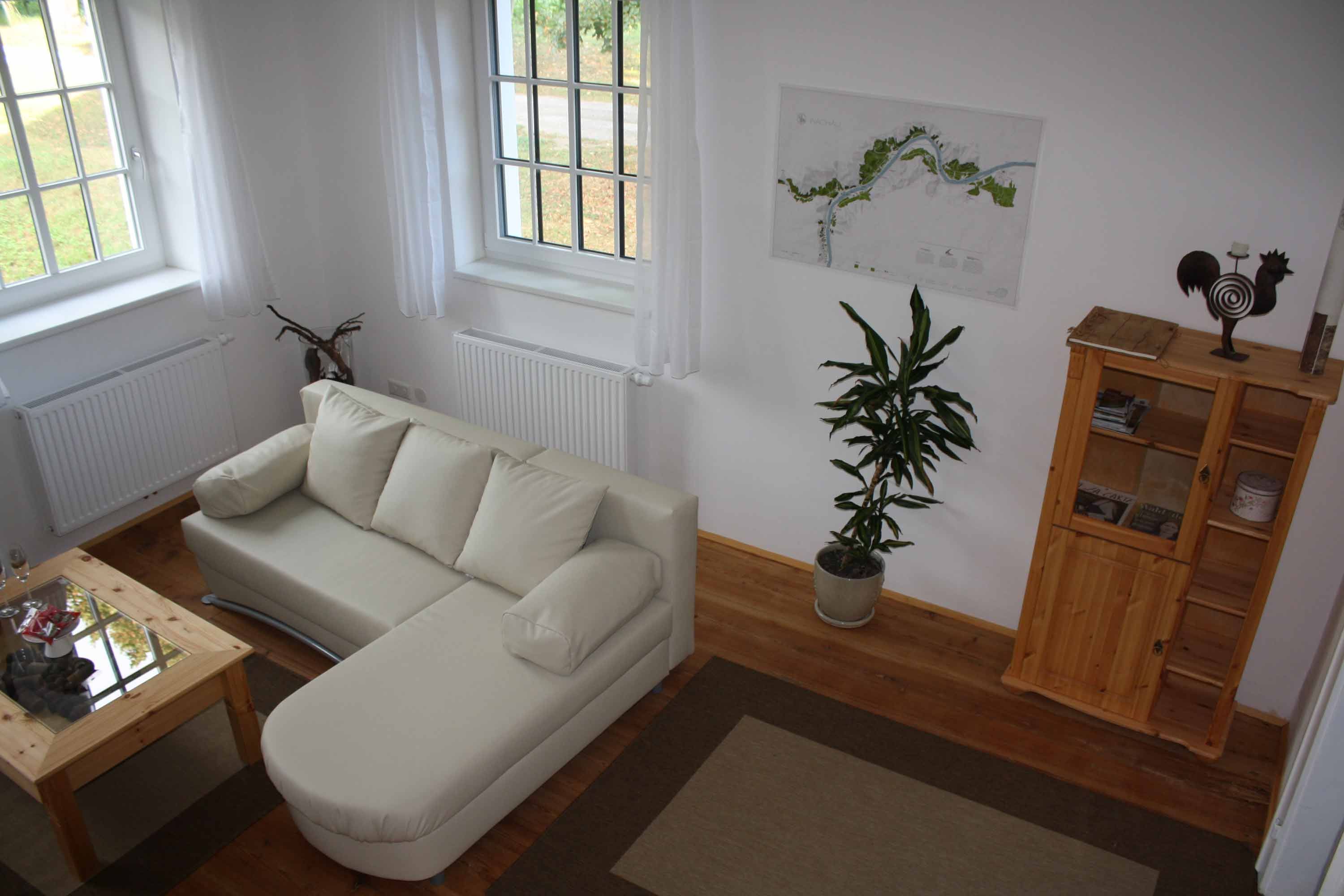 Útulný obývací priestor s béžovou pohovkou, dreveným stolom, rastlinou a policou v prázdninovom byte.