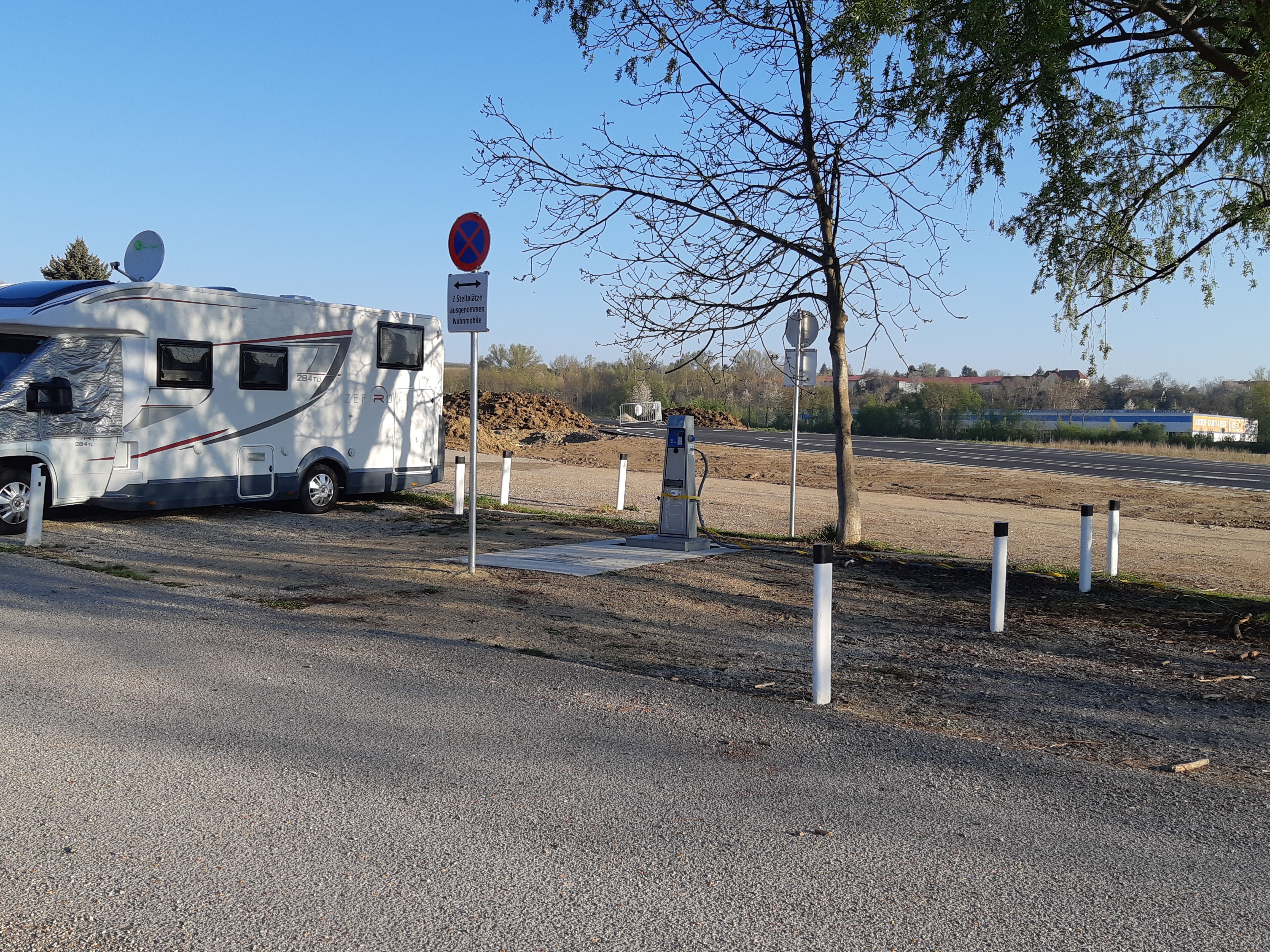 Karavan na ihrisku so značkami a stromami.