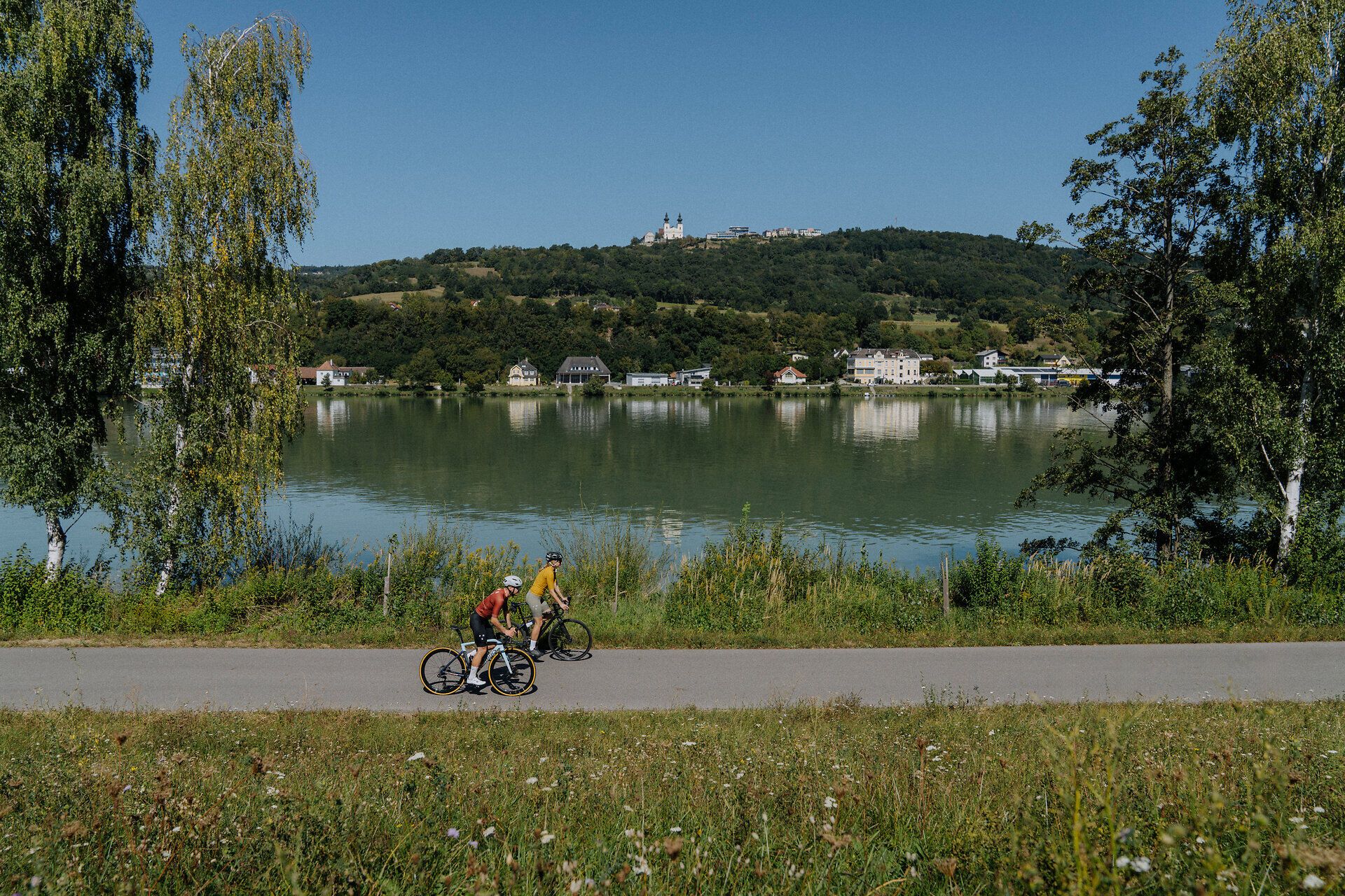 2 cyklisti na Dunajskej cyklotrase v Nibelungengau s výhľadom na Dunaj a Máriu Taferlovú