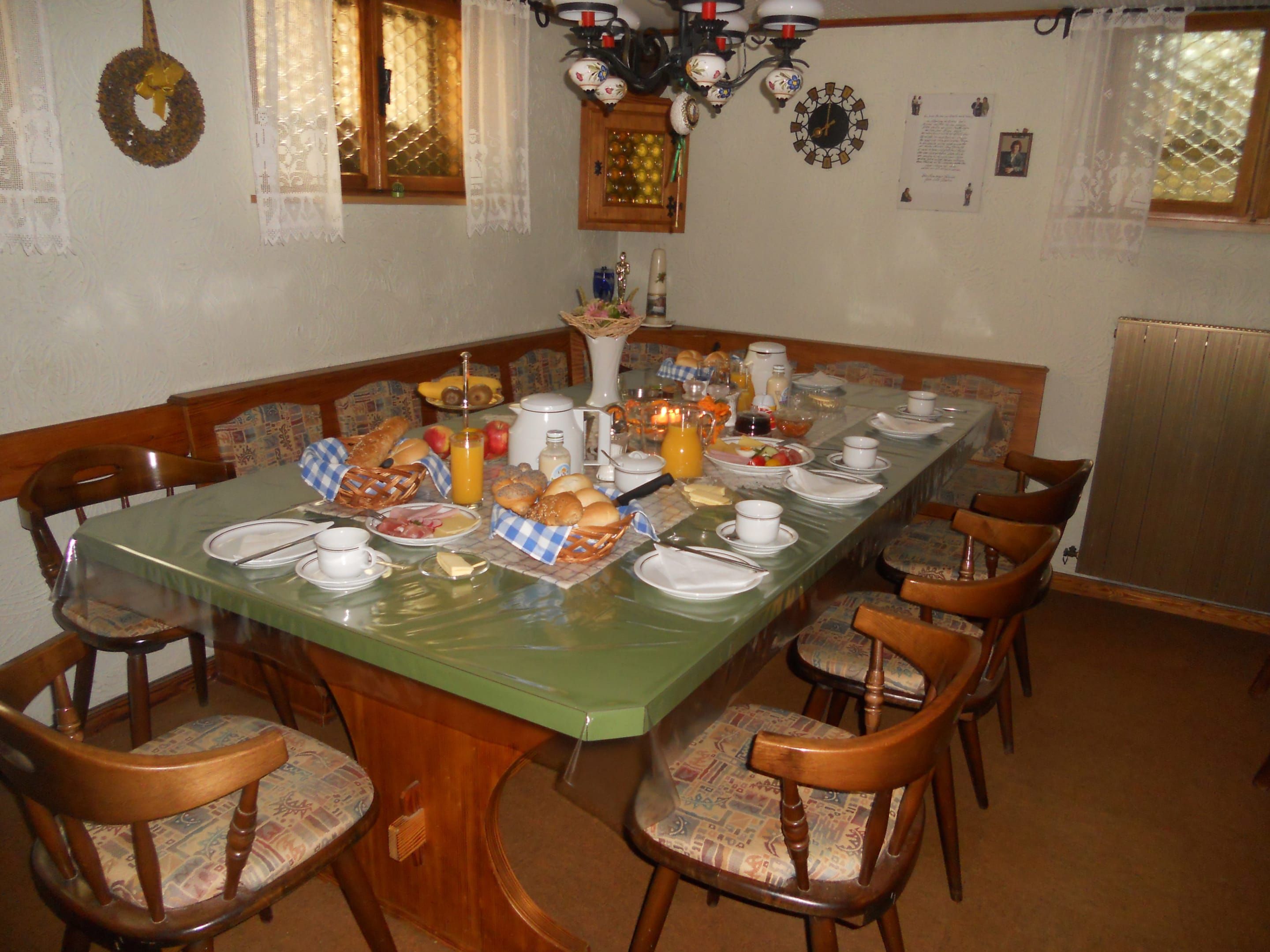 Raňajková miestnosť so stolom a stoličkami. Pri stole sa podávajú bohaté raňajky.