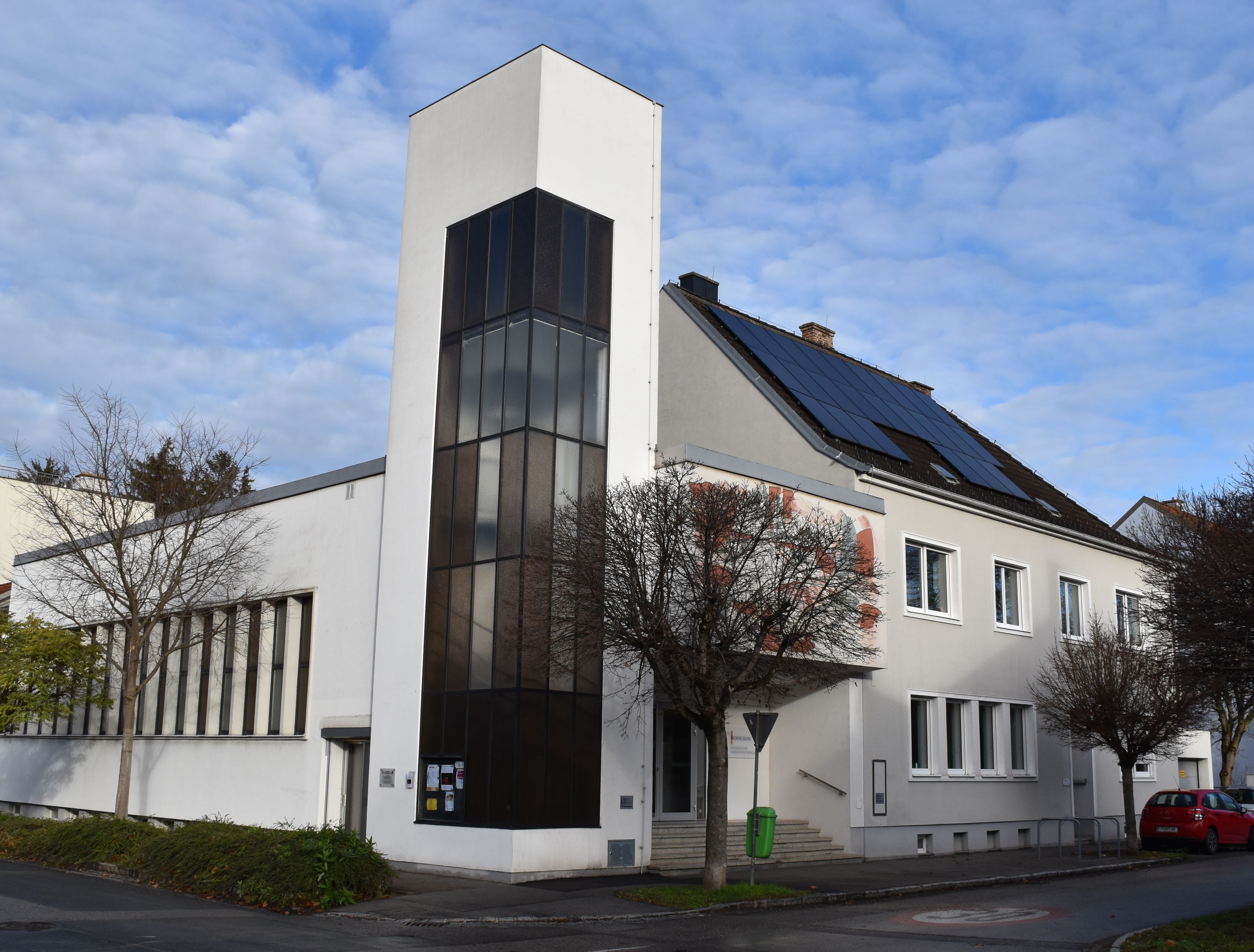 Moderný kostol s bielou fasádou a solárnymi panelmi na streche.