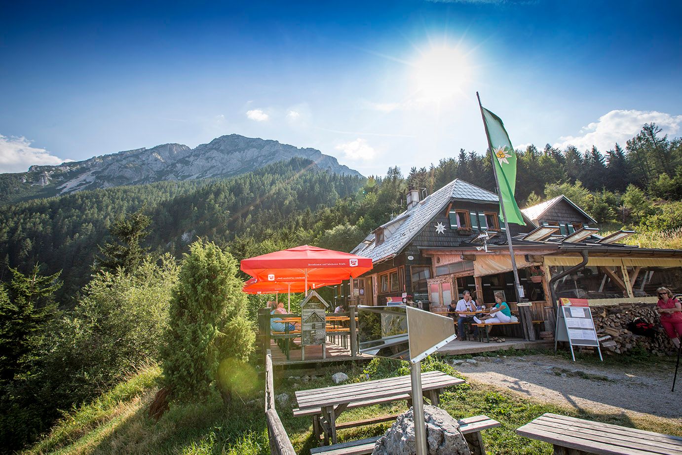 Chata Edelweiss na Schneebergu so slnečníkmi a horskou kulisou.