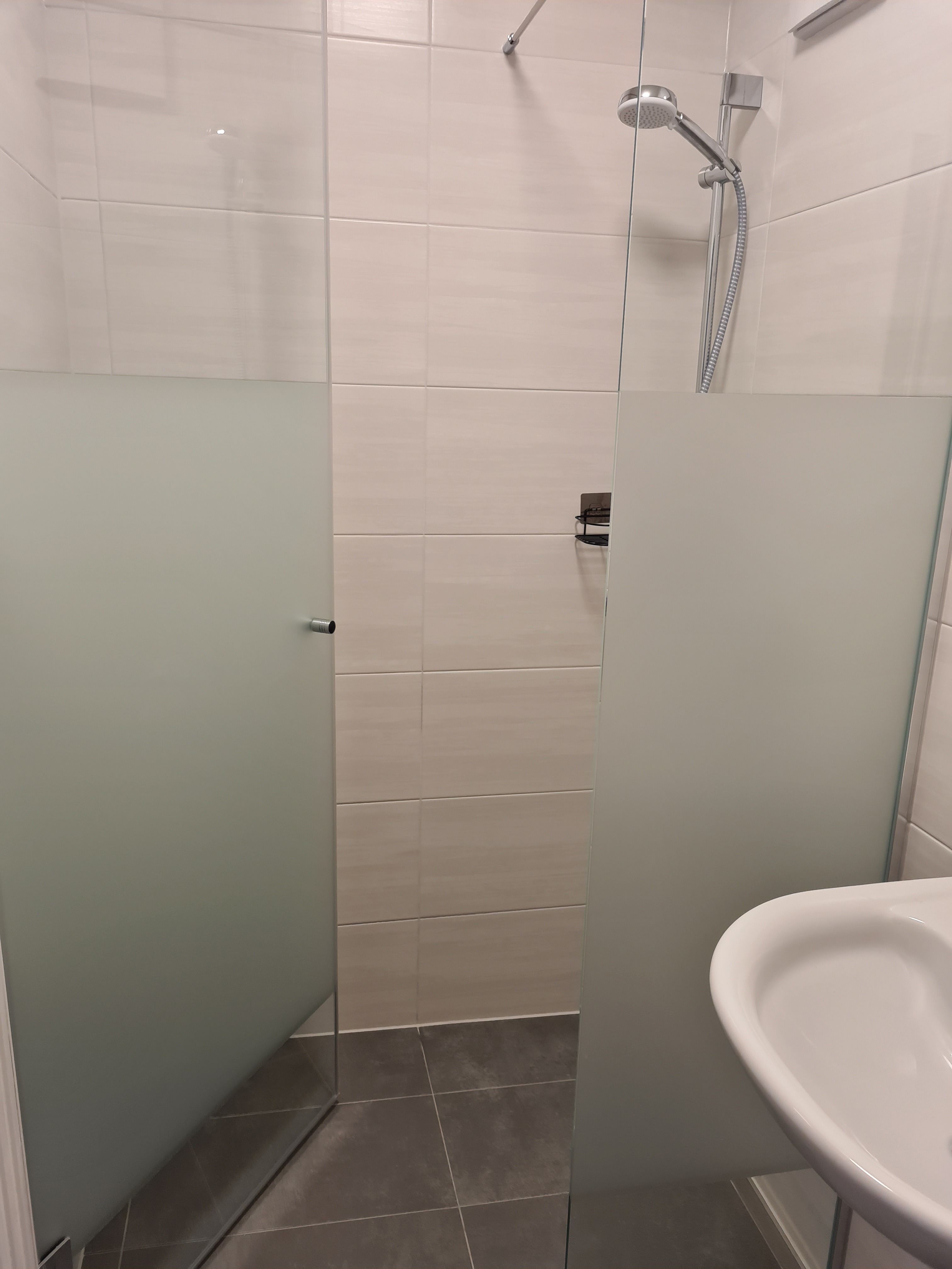 Moderná sprcha so sklenenými stenami a sprchovou hlavicou v kúpeľni.