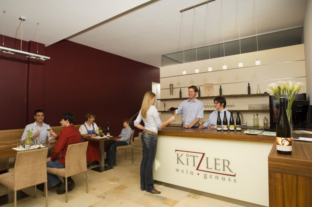 Pohľad do interiéru vinárne s hosťami a personálom.