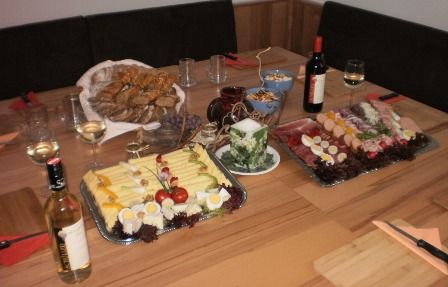 Prestretý stôl so syrovými a klobásovými taniermi, chlebom, vínom a pohármi.