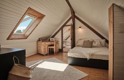 Rustikálny kamenný dom s drevenými dverami, lavičkou a kvetmi v popredí.