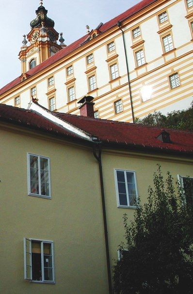 Žltá budova s červenou strechou pred kláštorom.