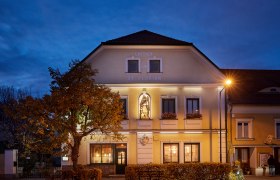 Hostinec svätého Floriána za súmraku s osvetlenou fasádou a sochou.