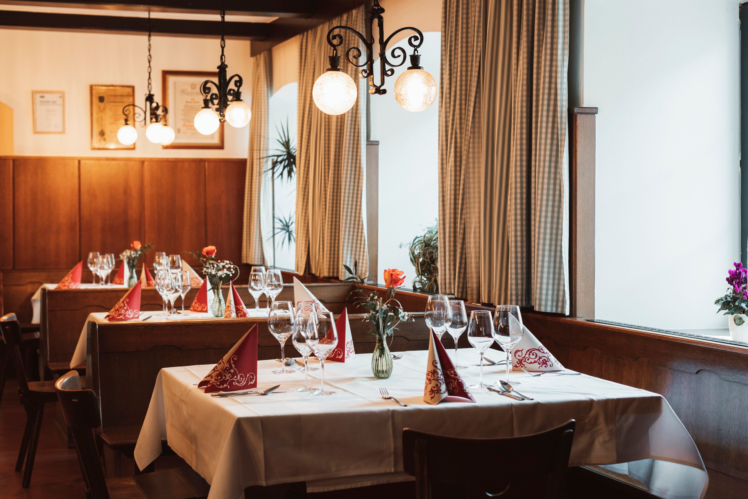 Útulná reštaurácia s prestretými stolmi, pohármi na víno a vázami na kvety.