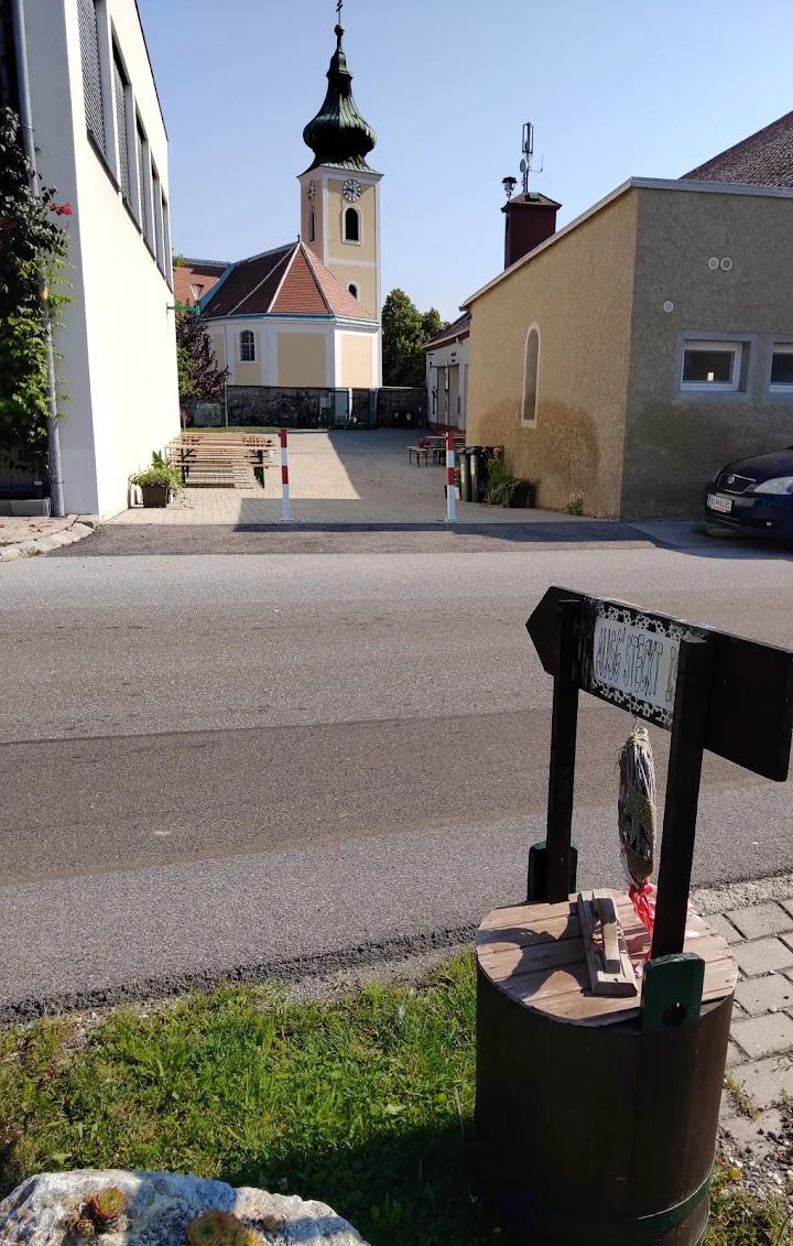 Vínny šenk Thaller Wolfsthal, pohľad na vnútorné nádvorie so stolmi na víno, v pozadí vidno kostol 