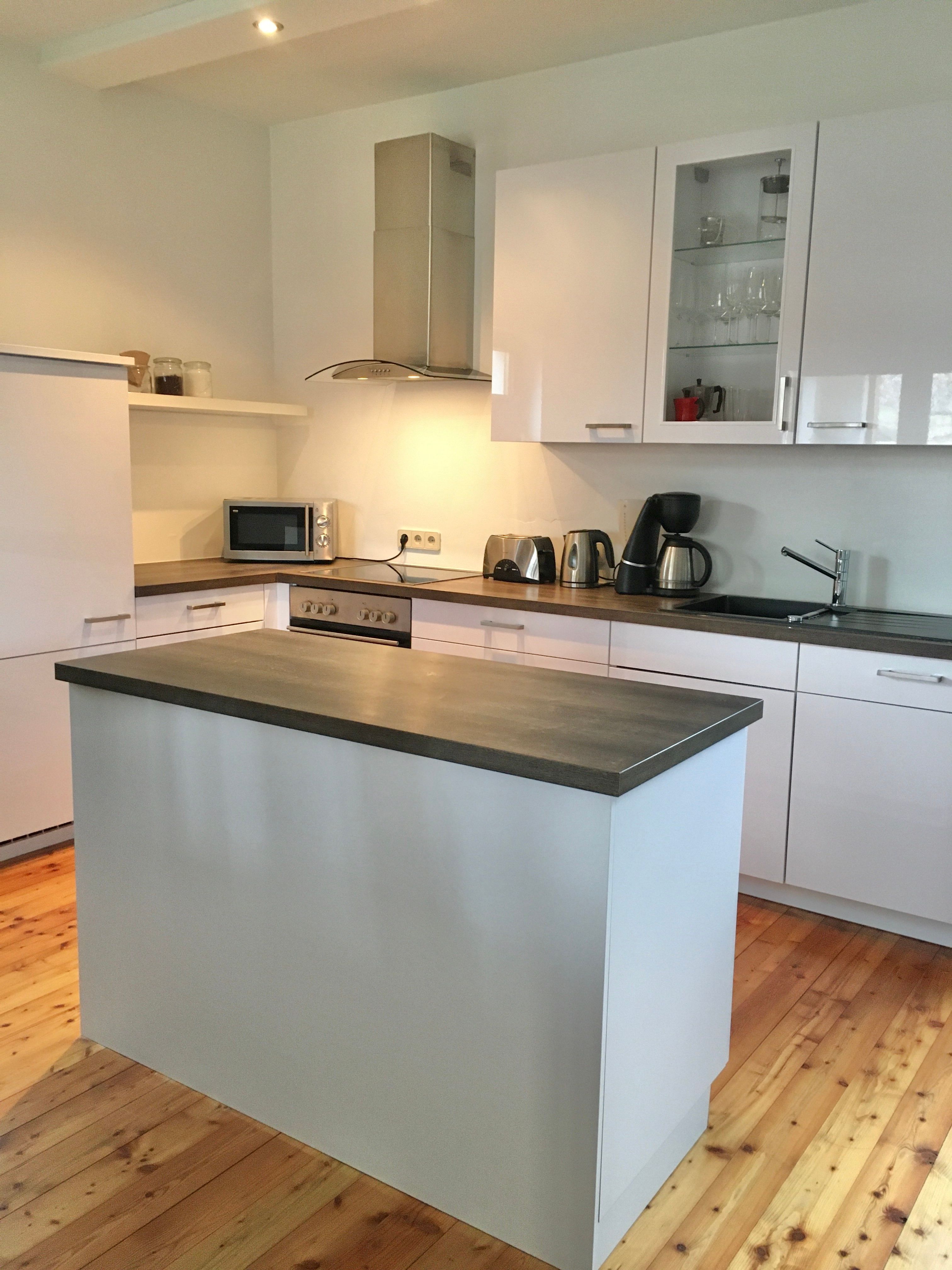 Moderná kuchyňa s ostrovom, bielymi skrinkami a spotrebičmi.