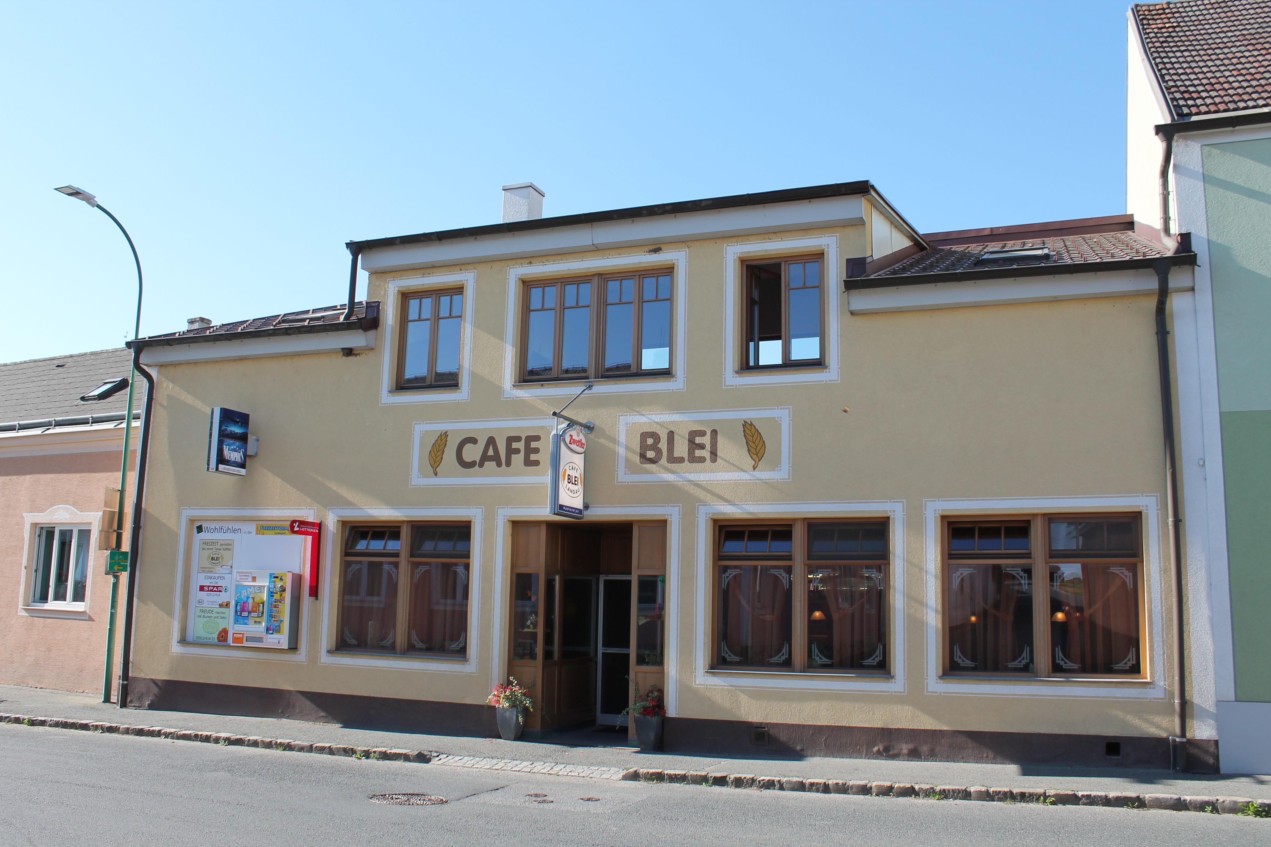 Exteriérový pohľad na kaviareň Café Blei so žltou fasádou a veľkými oknami.