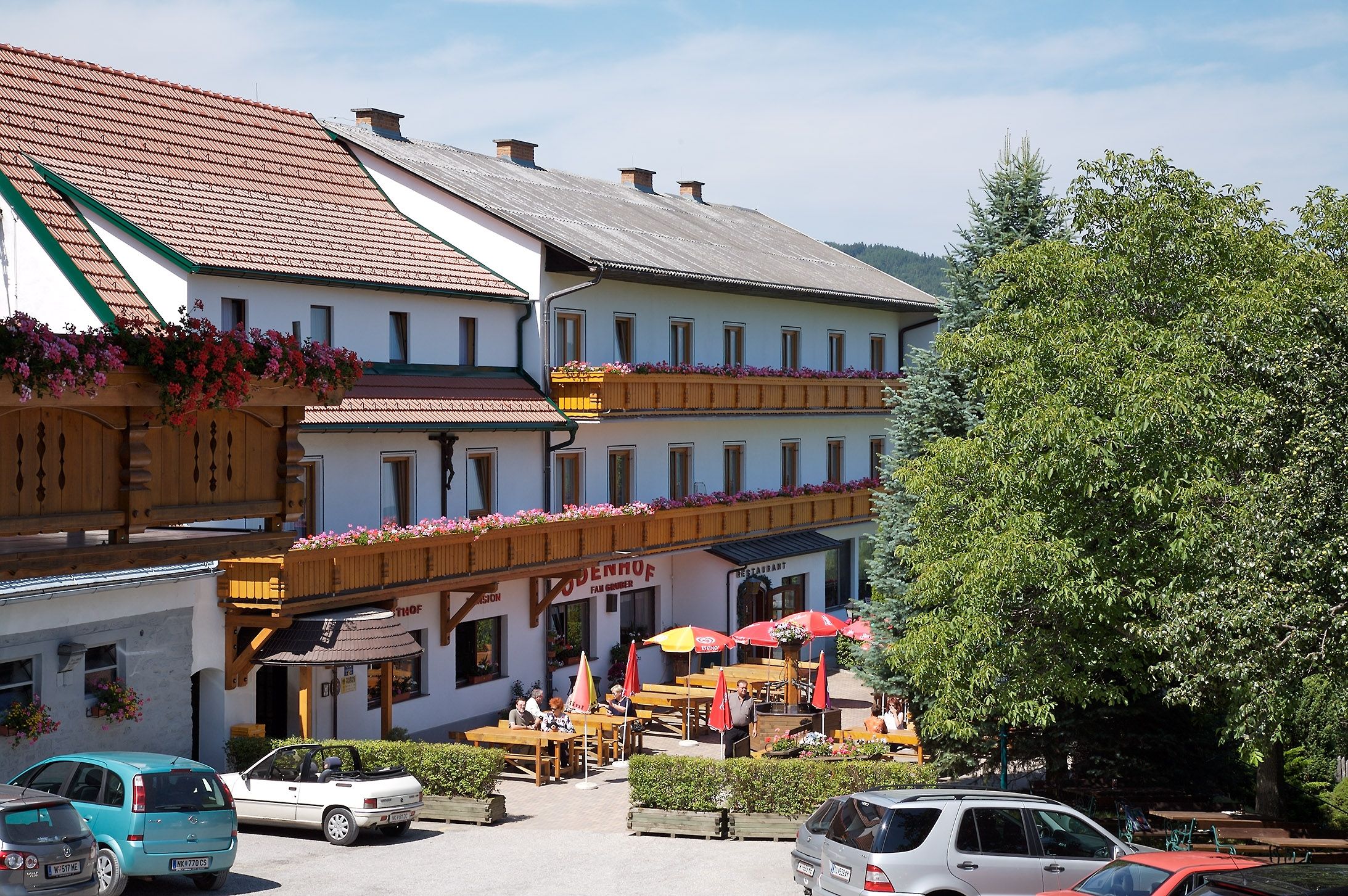 Gasthof-Pension Ödenhof s terasou a zaparkovanými autami.