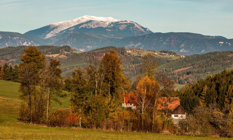 Krajina s horami, stromami a domom na jeseň.