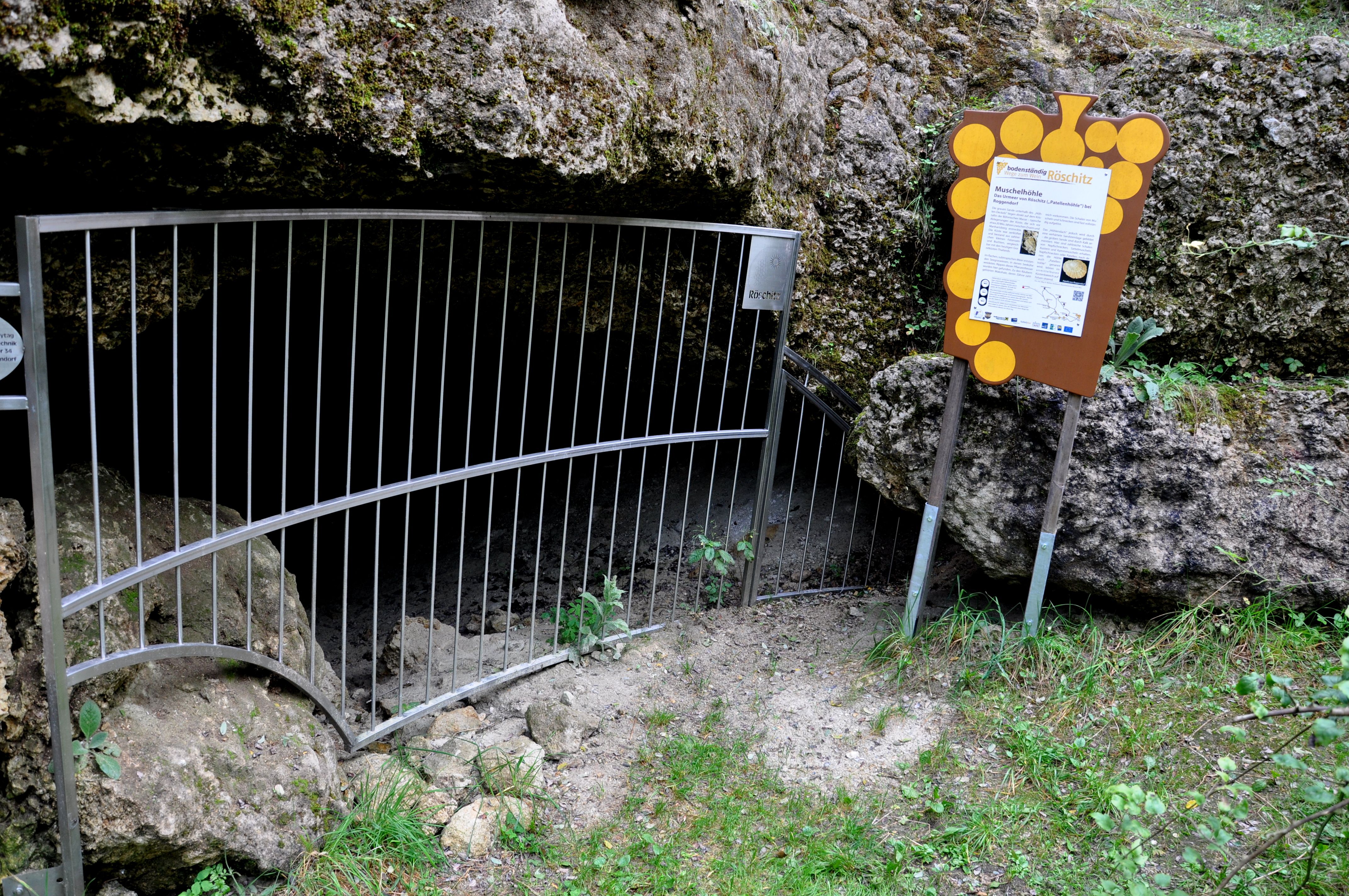 Vchod do jaskyne Röschitz s mriežkou a informačnou tabuľou.