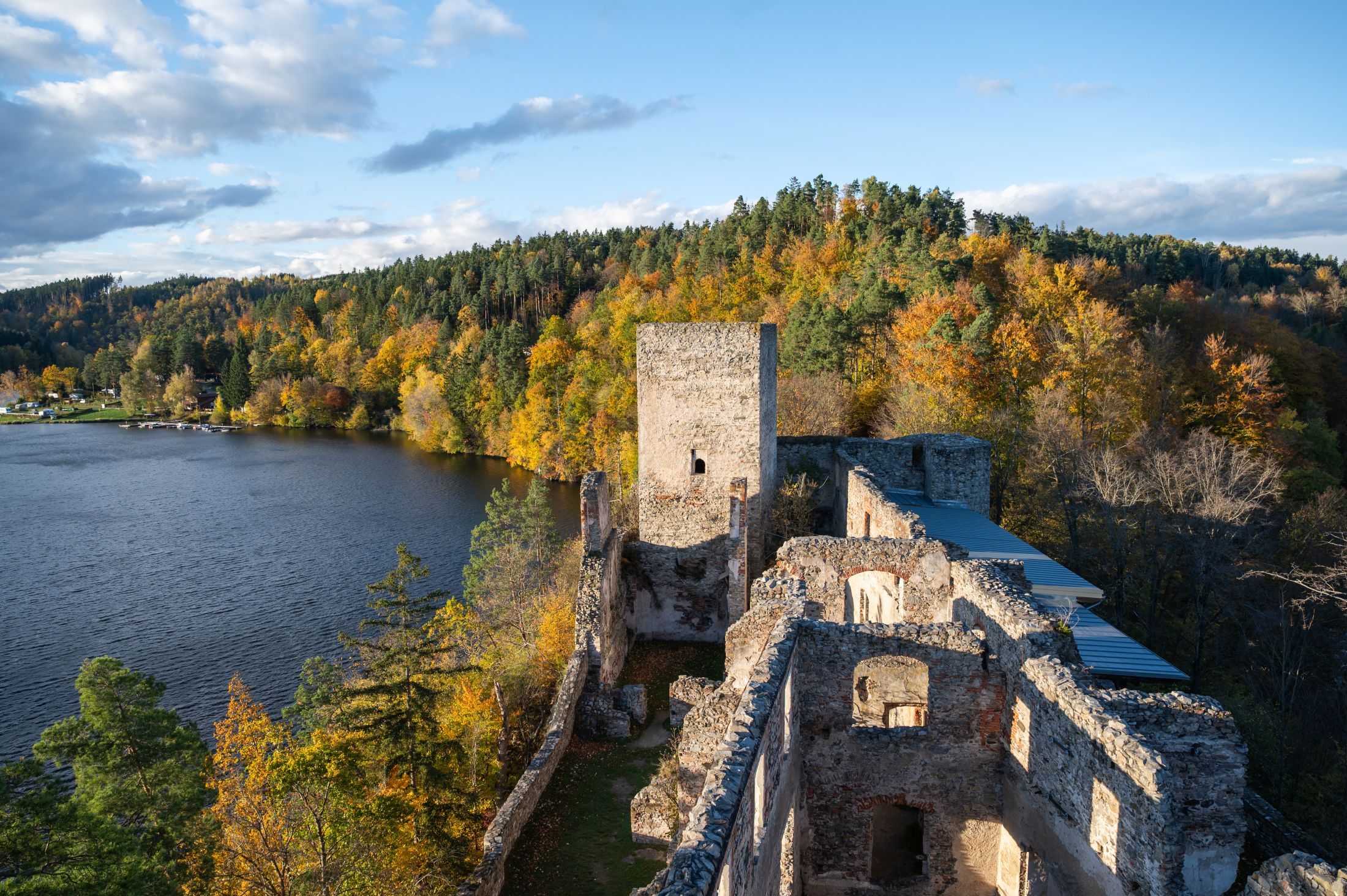 Zrúcanina Dobra s výhľadom na jazero a jesenný les.
