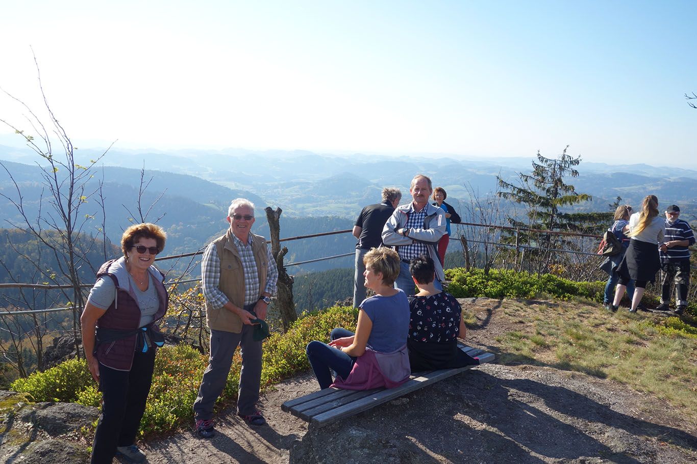 Ľudia si vychutnávajú výhľad z vrcholu hory so širokým výhľadom na krajinu.