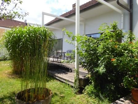 Terasa s rastlinami a záhradným nábytkom pred bielym domom.