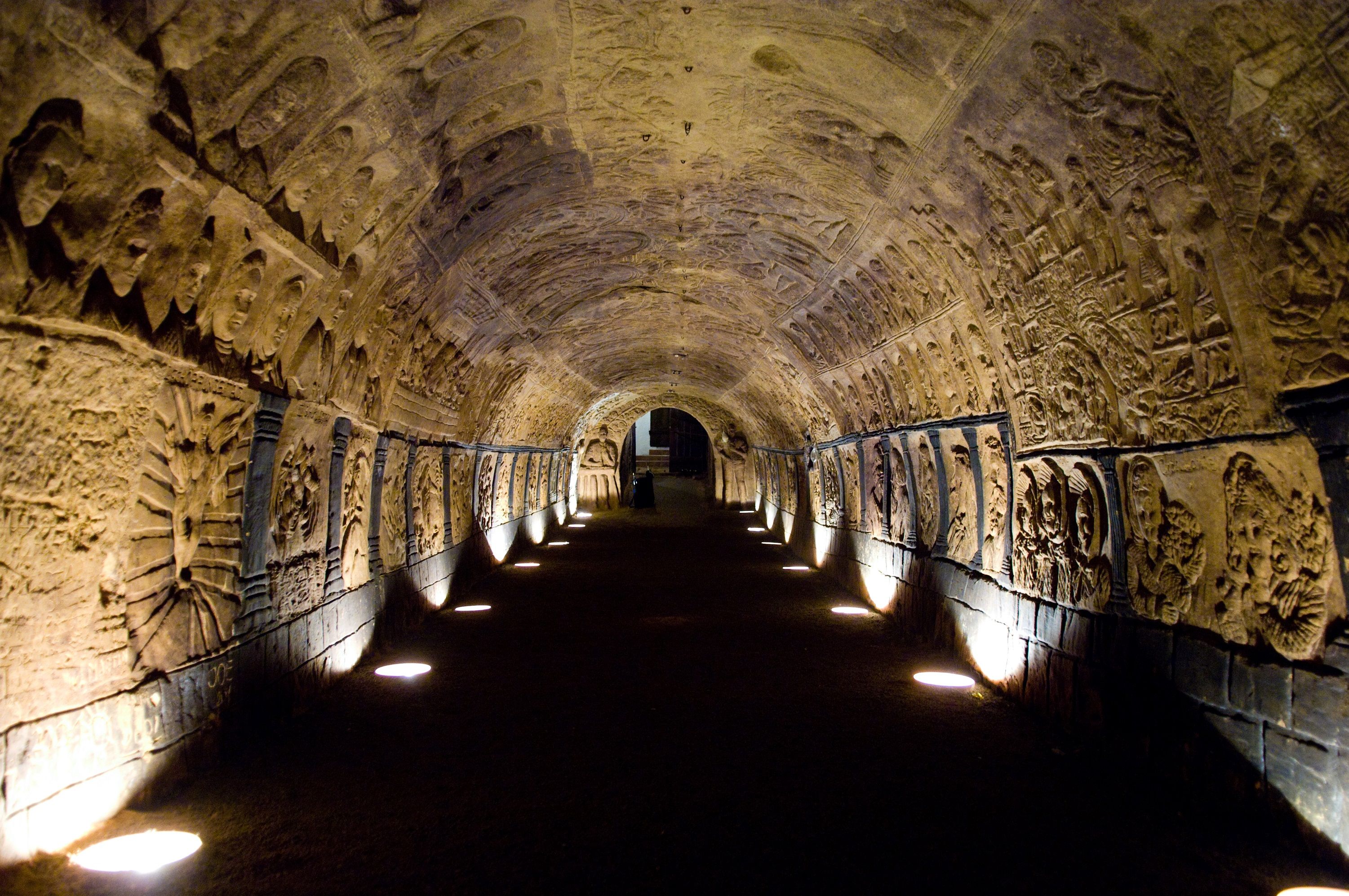Osvetlený tunel zdobený reliéfmi v historickej pivnici.