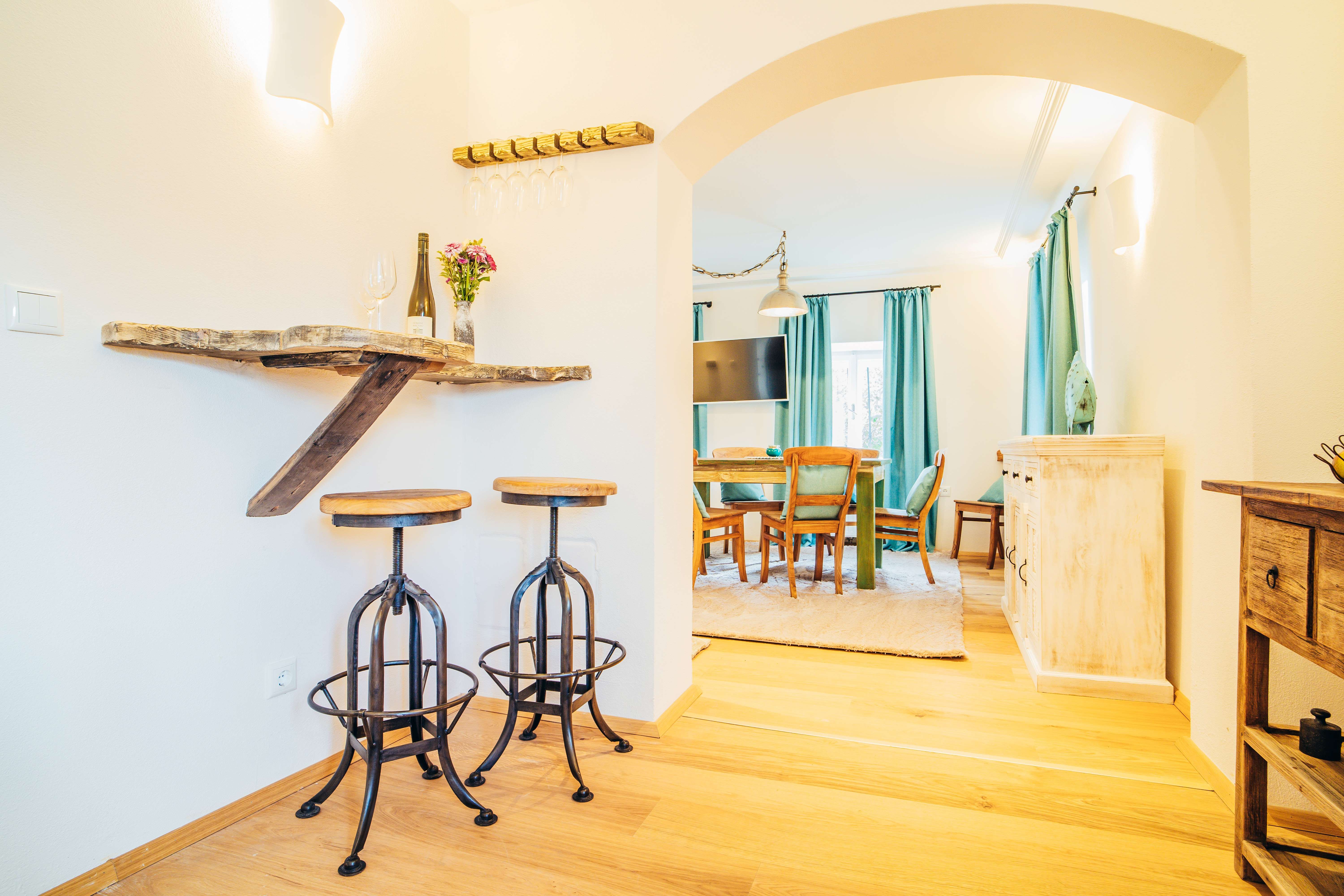 Útulná obývacia izba s dreveným nábytkom, barovými stoličkami a jedálenským stolom.