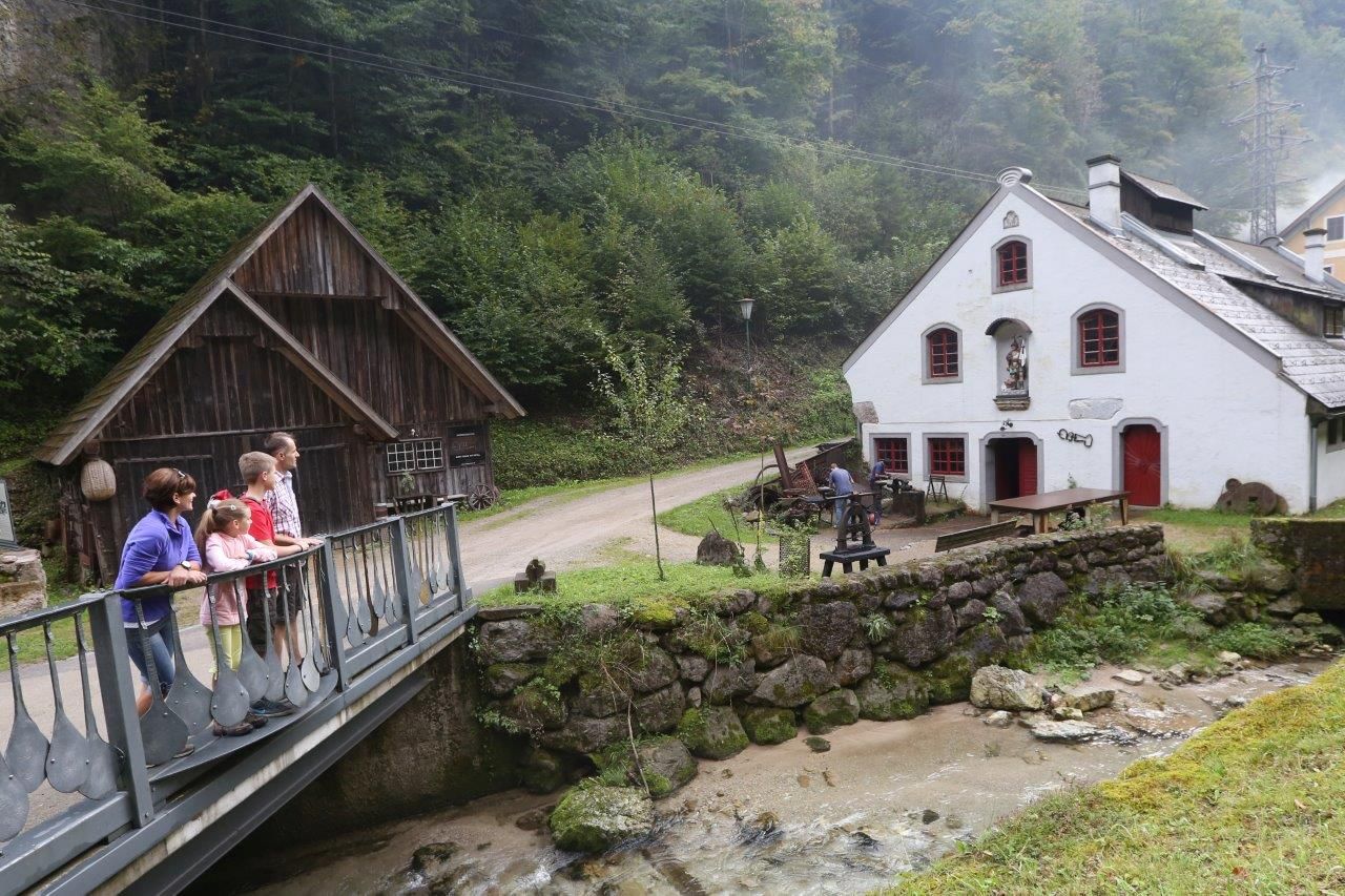 Rodina stojí na moste pred historickou budovou na vidieku.