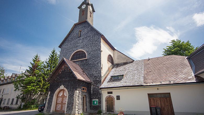 Farský kostol Josefsberg s kamennou fasádou a vežou pod modrou oblohou.
