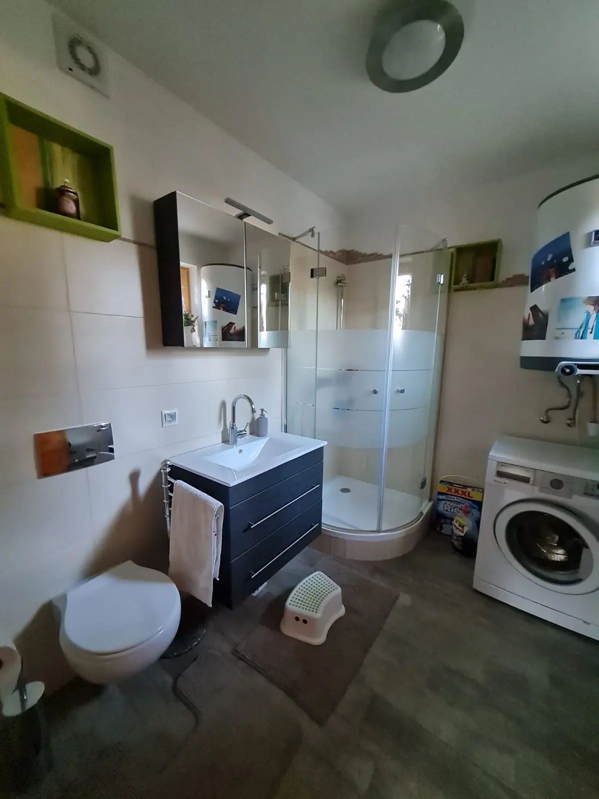 Moderná kúpeľňa so sprchovacím kútom, umývadlom, WC a práčkou.