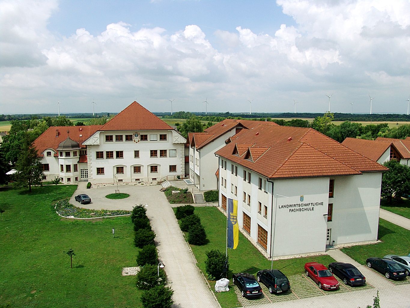 Letecký pohľad na komplex školských budov s červenými strechami a okolitou zeleňou.