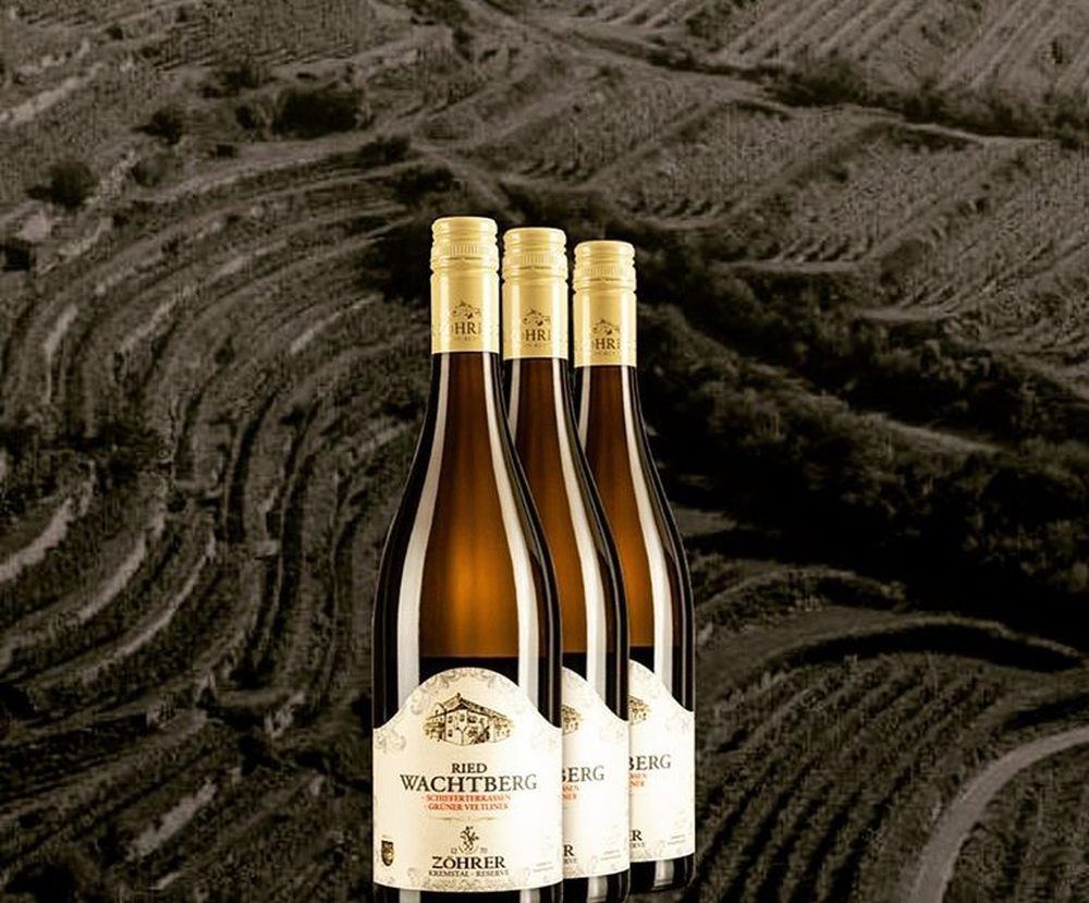 Tri fľaše vína na pozadí vinohradov.