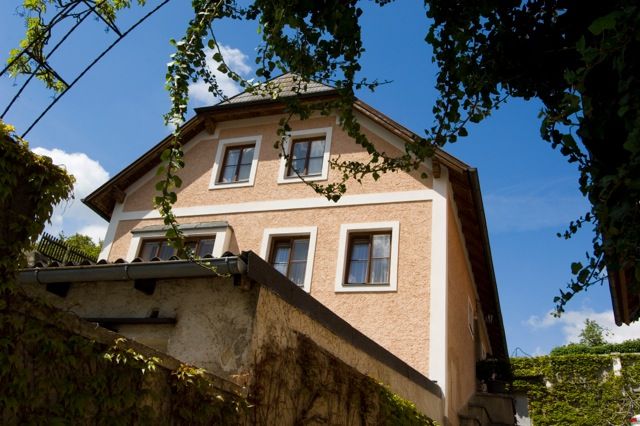 Pohľad zvonka na tradičný dom obrastený brečtanom, v pozadí modrá obloha.