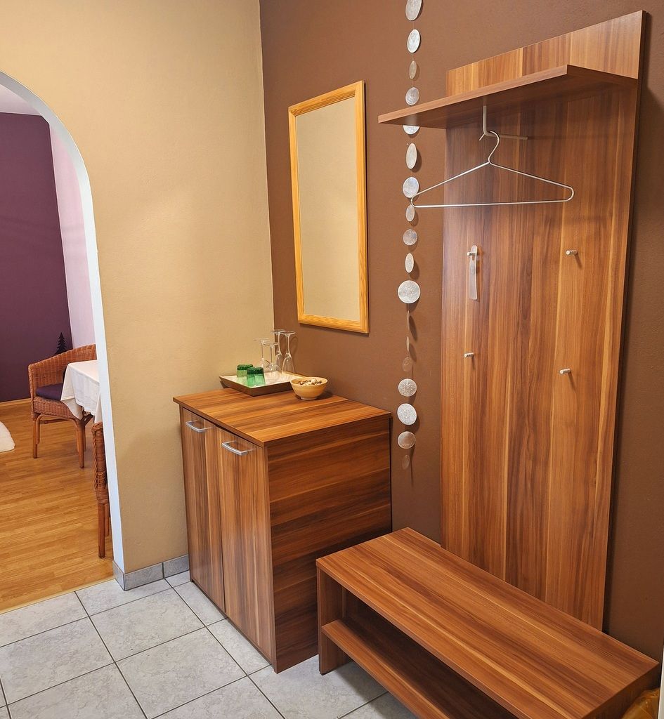 Moderný vstupný priestor s dreveným nábytkom, zrkadlom a dekoráciami.