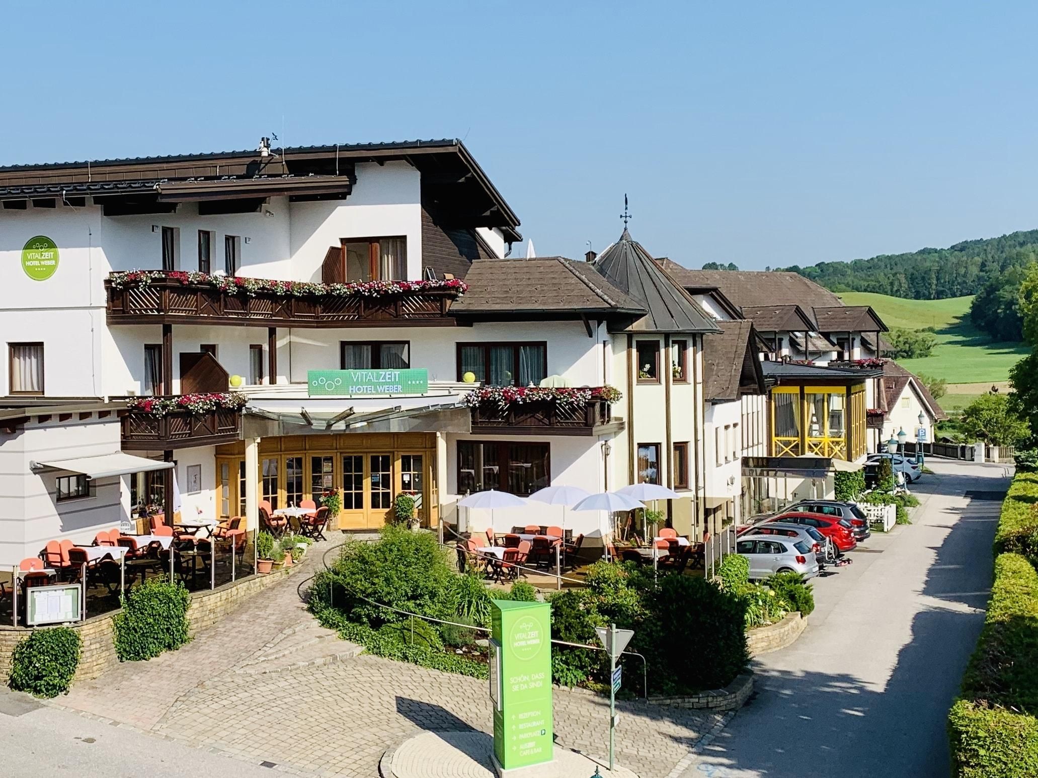 Exteriérový pohľad na hotel VitalZeit Weber s terasou a okolitou krajinou.