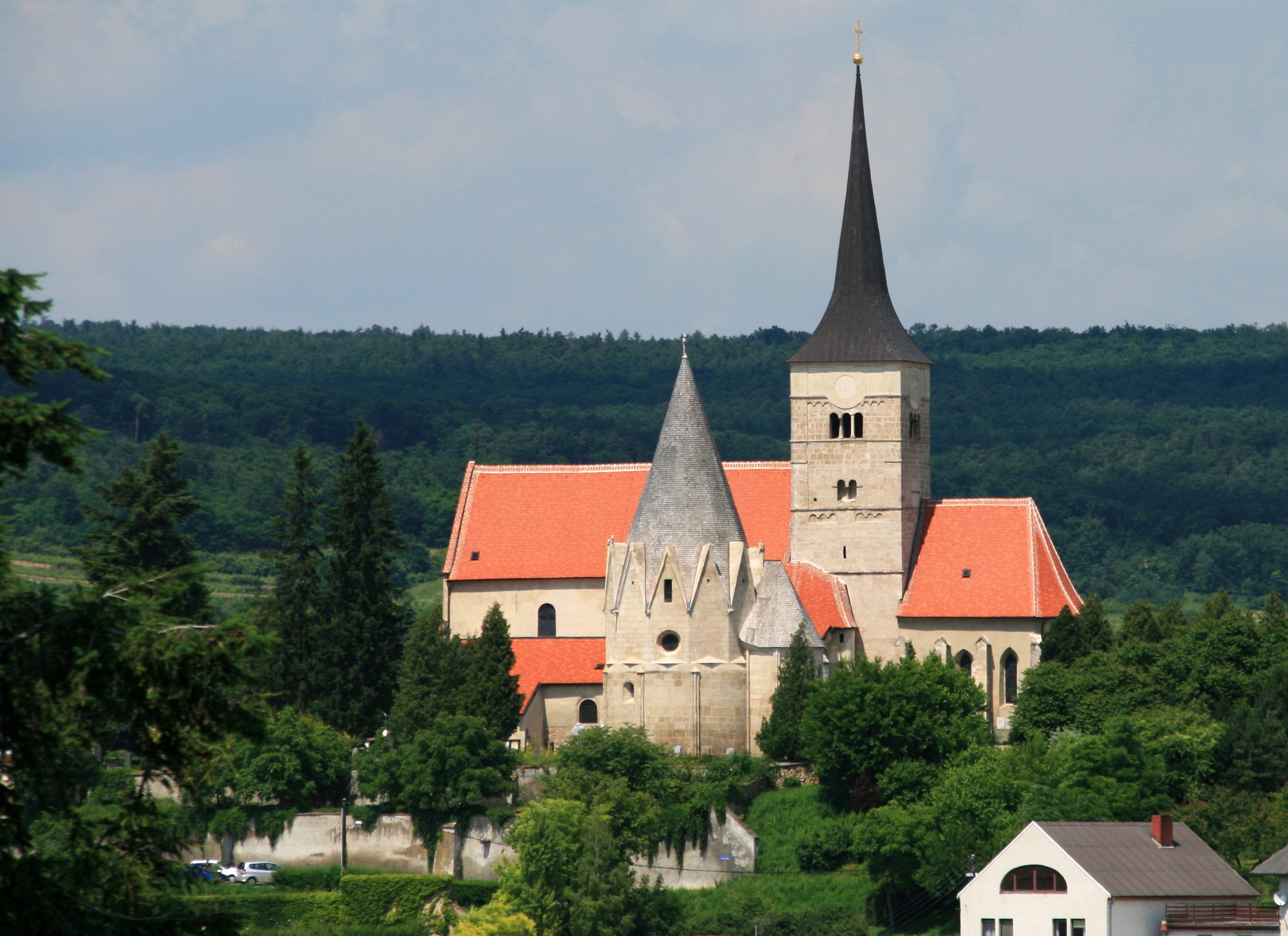 Michala v Pulkau s červenou strechou a špicatou vežou, obklopený stromami.