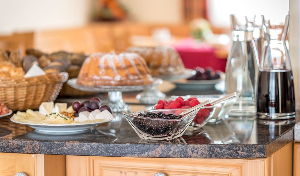 Raňajkový bufet s koláčmi, bobuľovým ovocím, syrovou misou a nápojmi na stole.