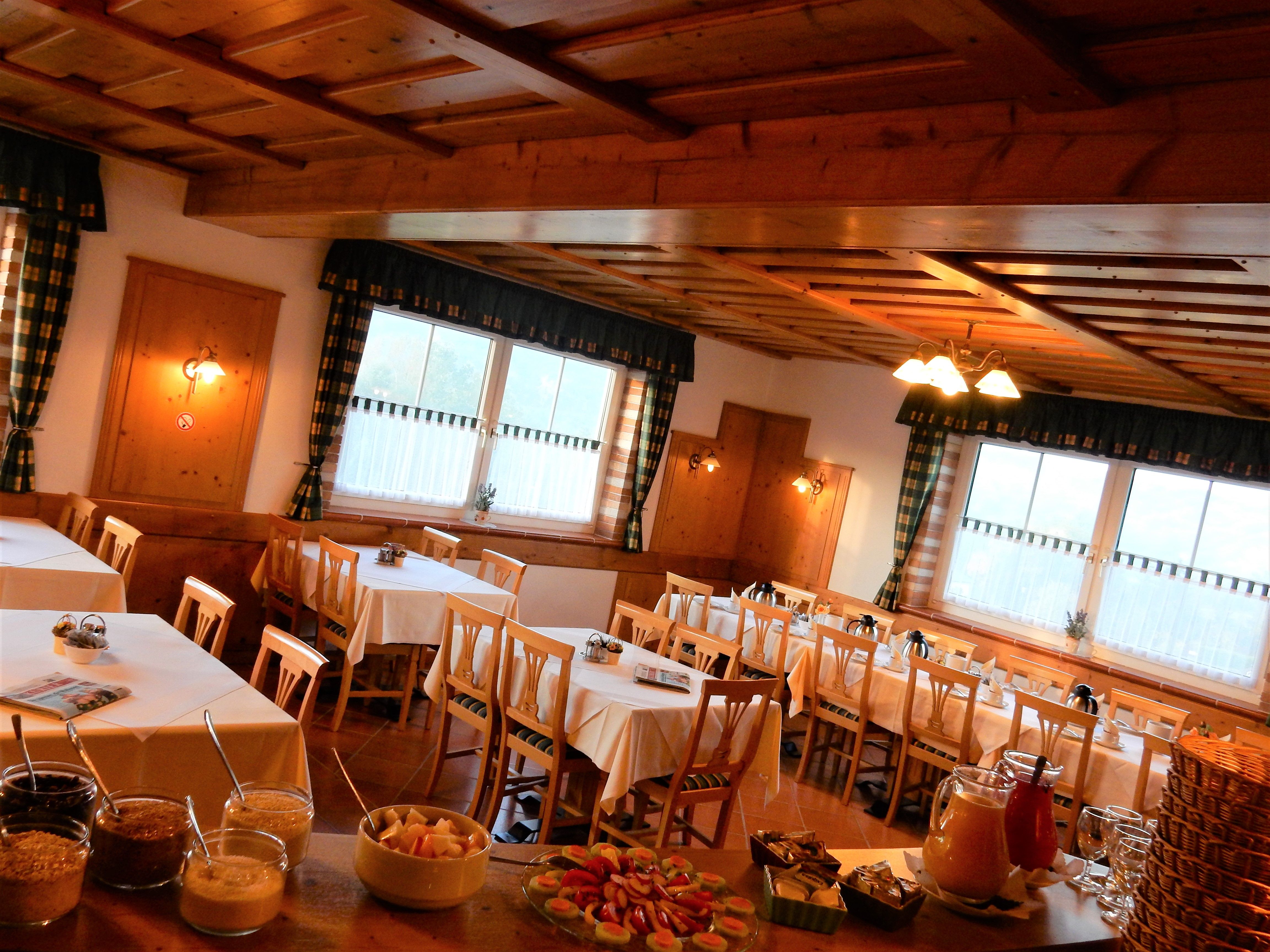 Útulná raňajková miestnosť s dreveným nábytkom a prestretými stolmi.